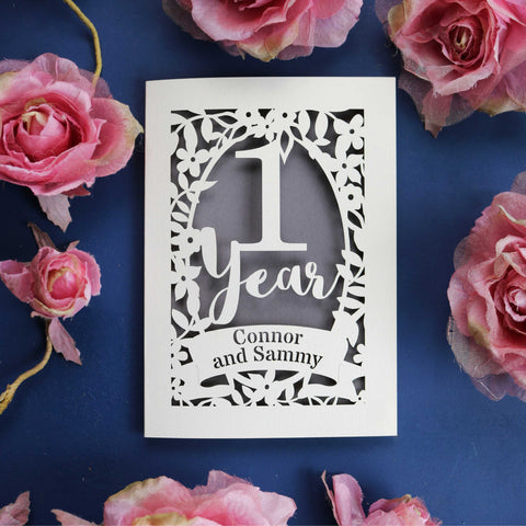 A personalised anniversary card with 1 year in script font surrounded by flowers, and a banner with the first names of the couple inside.  - A5 (large); / Urban Grey