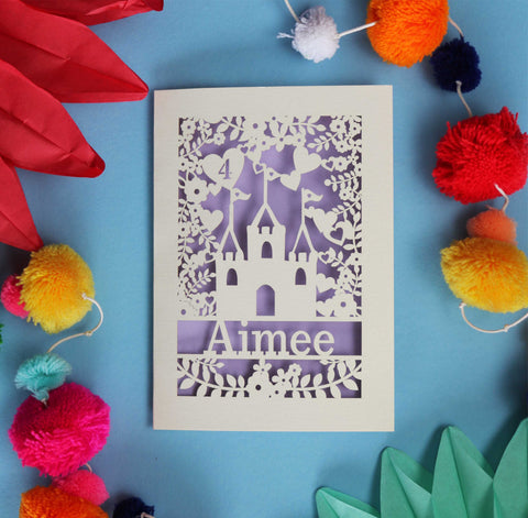 A laser cut birthday card for girls. A cream card with a princess castle and hearts and flowers. Personalised with an age and a name, and hand finished with a lilac paper insert.