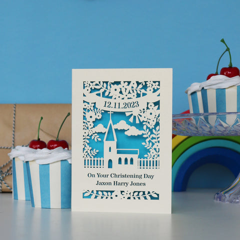 A cream and blue card for Christenings. Cut away card reveals blue paper behind and forms the shape of a church and flowers. Cut away text has the date at the top, "On Your Christening Day" and the name at the bottom. - A5 (large) / Peacock Blue
