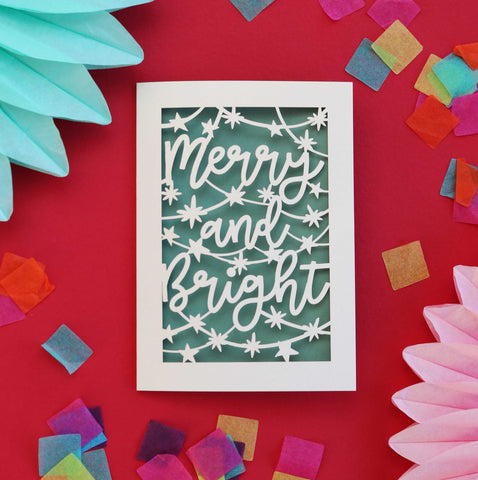 Laser cut Christmas cards that say "Merry and Bright", surrounded by stars.