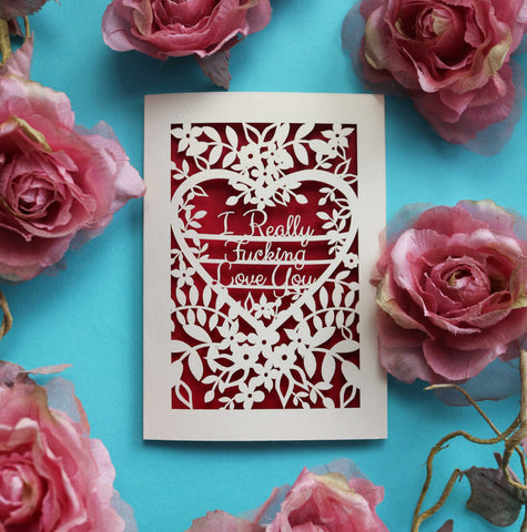 A laser cut Valentine card that says "I really fucking love you" surrounded by flowers and leaves