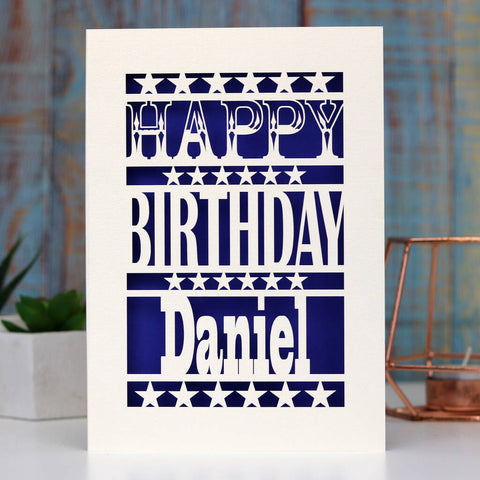A paper cut birthday card for him. Happy Birthday Daniel is written on the front of the card. Card can be personalised with any name. Stars separate each line of text and background is violet. - A5 / Infra Violet