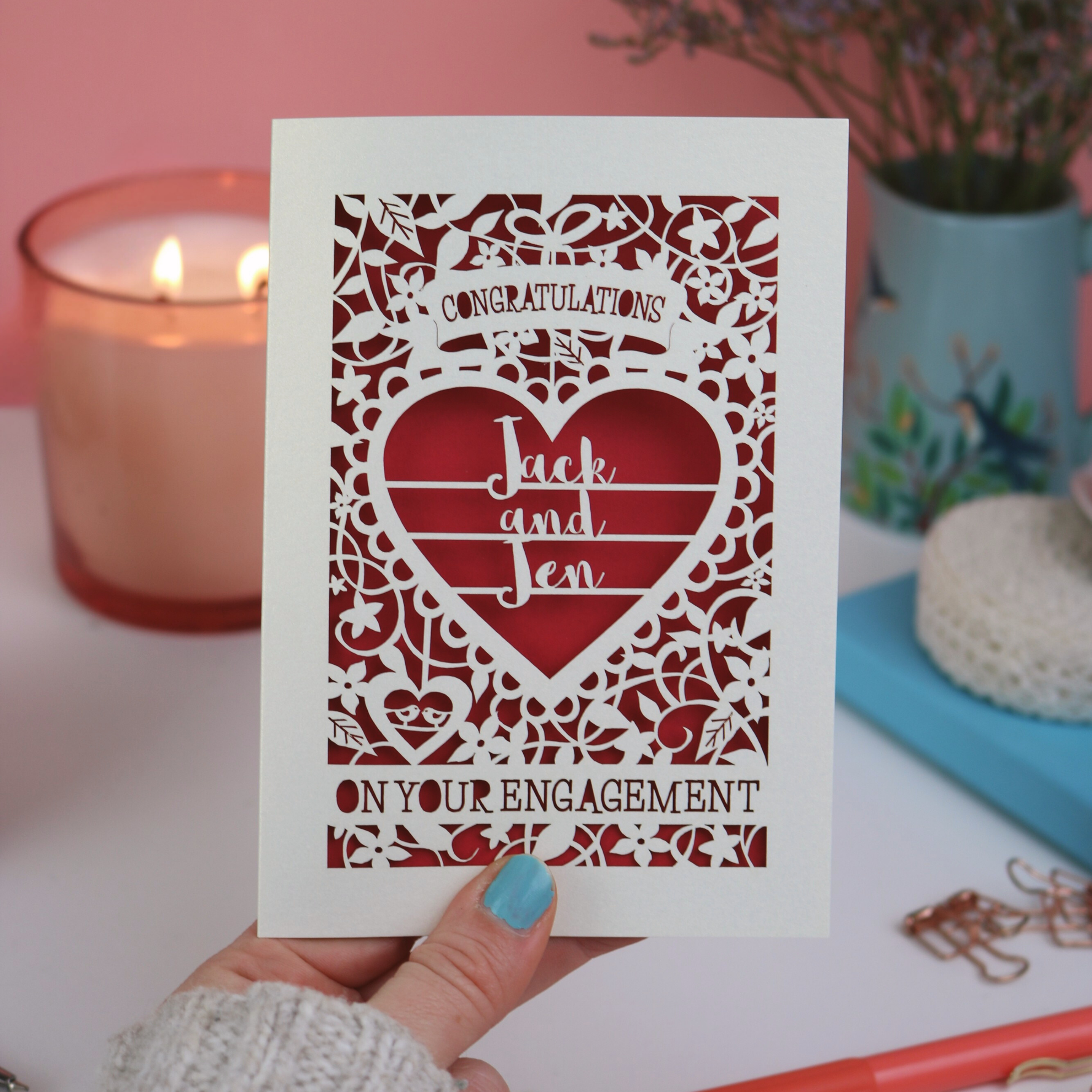 A personalised laser cut engagement card on pink background