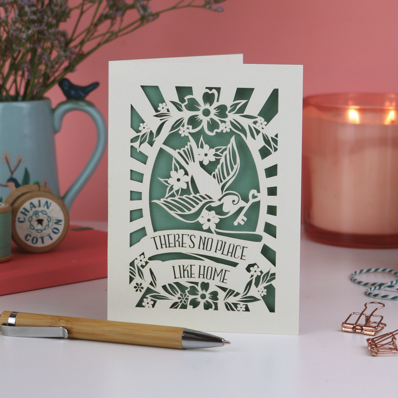 A laser cut new home card on pink background