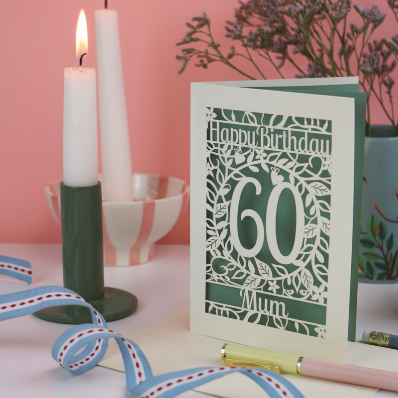 A laser cut birthday card on desk with pink background, candles and ribbon