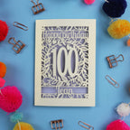 Laser cut 100th birthday card with decorative elements on a blue background