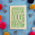 Laser cut 100th birthday card with decorative elements on a blue background