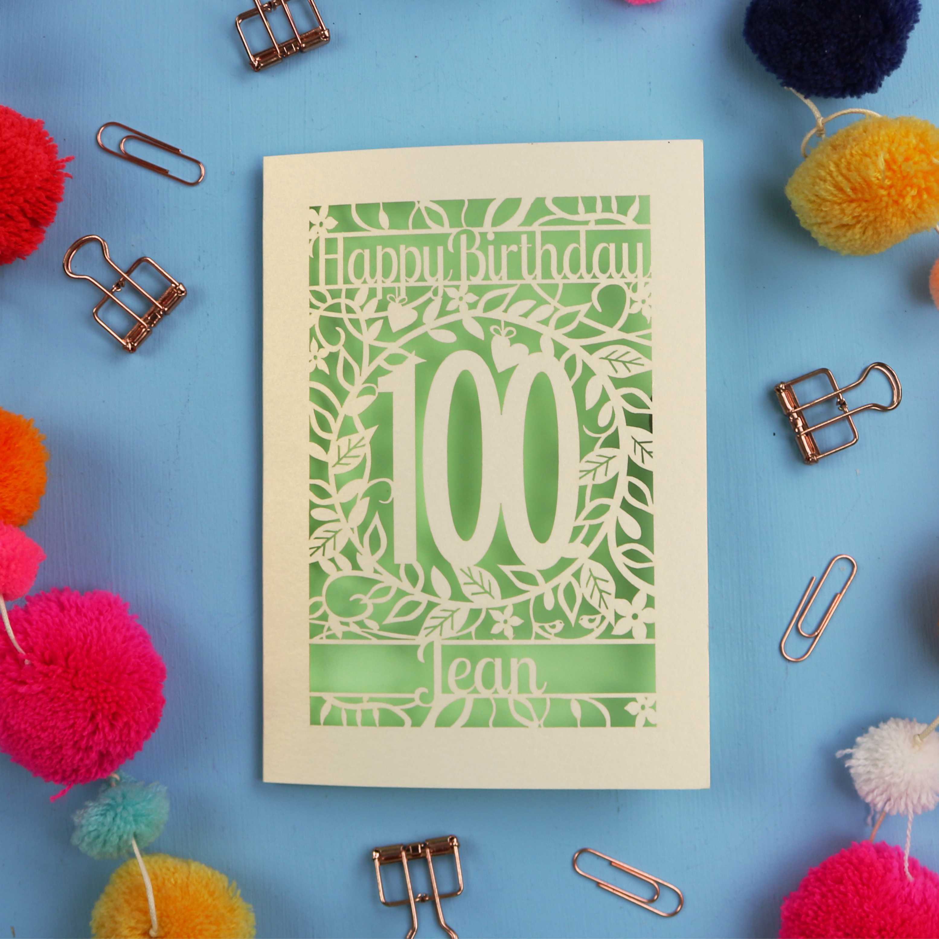 Laser cut 100th birthday card with decorative elements on a blue background