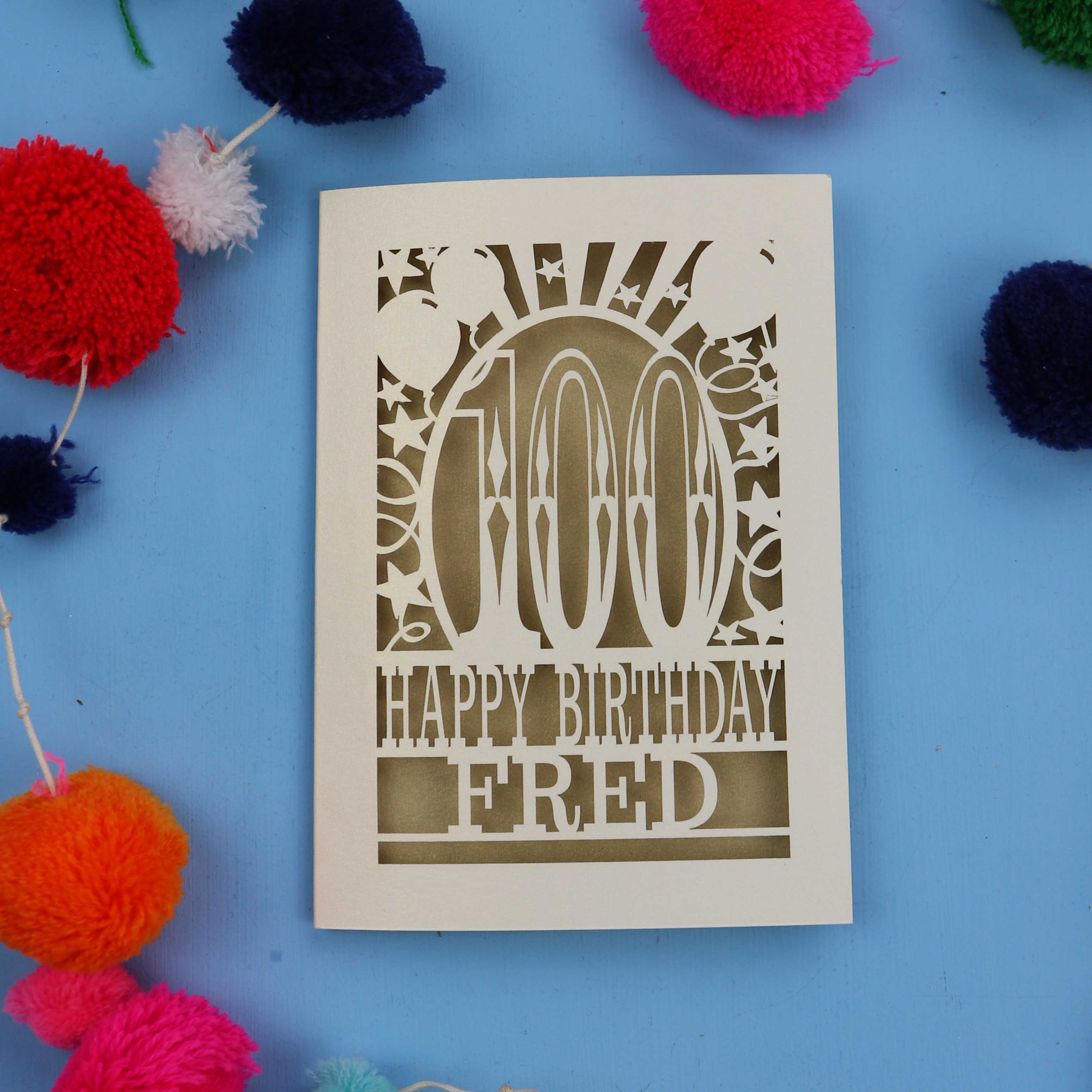 100th Birthday card with 'Happy Birthday Fred' text on a blue background with colourful pom-poms.