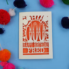 Special 100th Birthday card with 'Happy Birthday Fred' text on a blue background with colourful pom-poms.