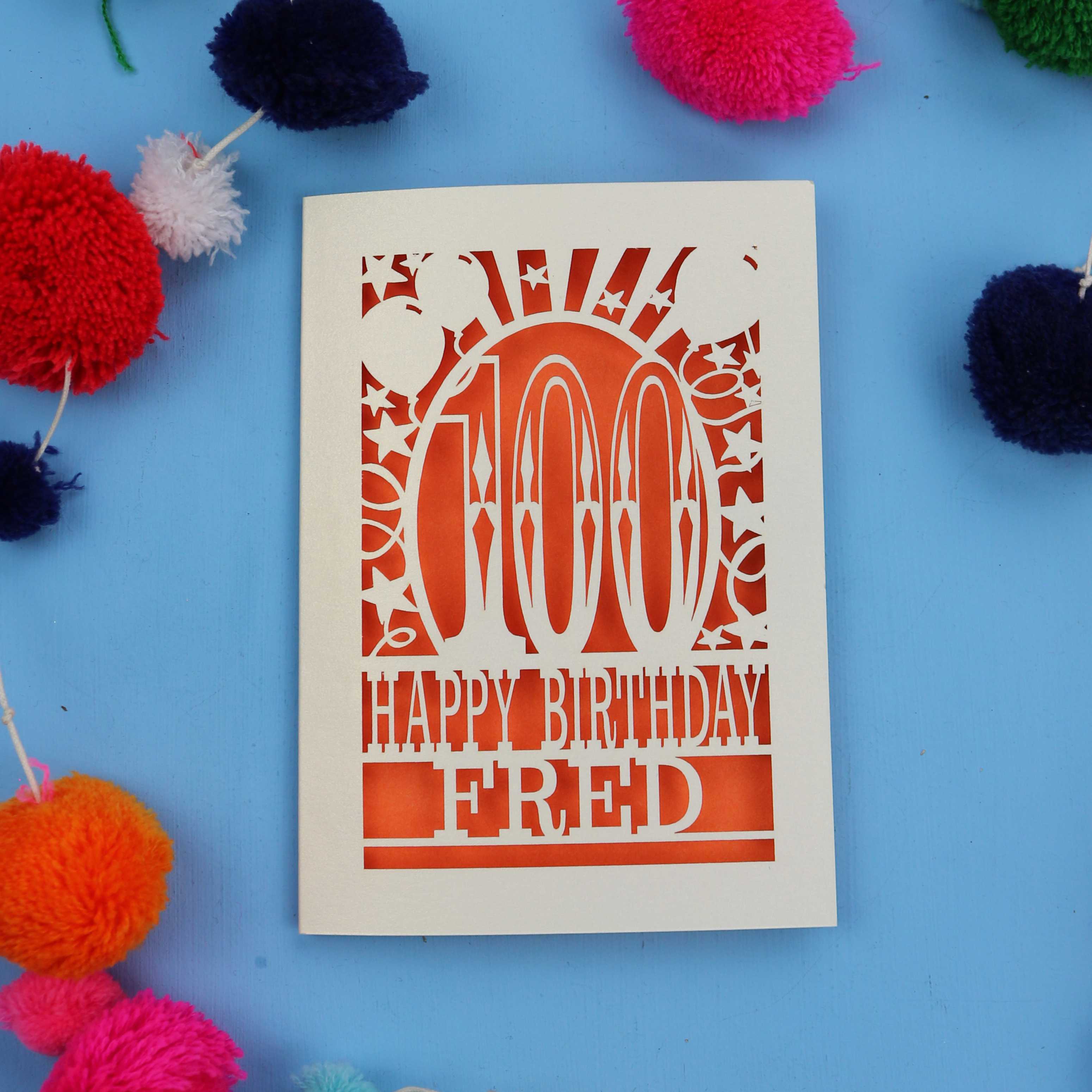 Special 100th Birthday card with 'Happy Birthday Fred' text on a blue background with colourful pom-poms.