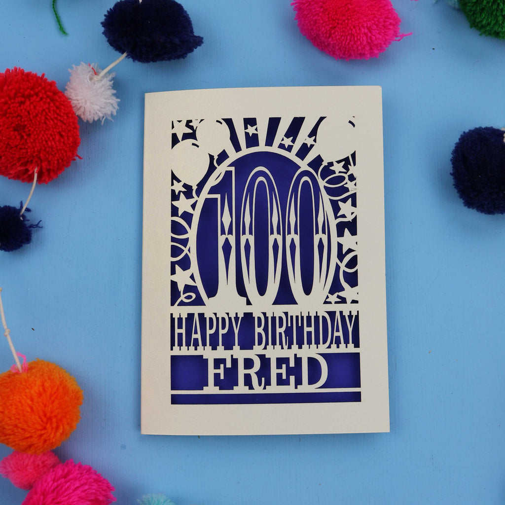 100th Birthday card with 'Happy Birthday Fred' text on a blue background with colourful pom-poms.