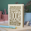 A laser cut 100th birthday card with floral '100' cut out design, 'Happy Birthday' text, and personalised with a name. 