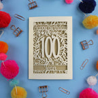 Laser cut 100th birthday card with decorative elements on a blue background