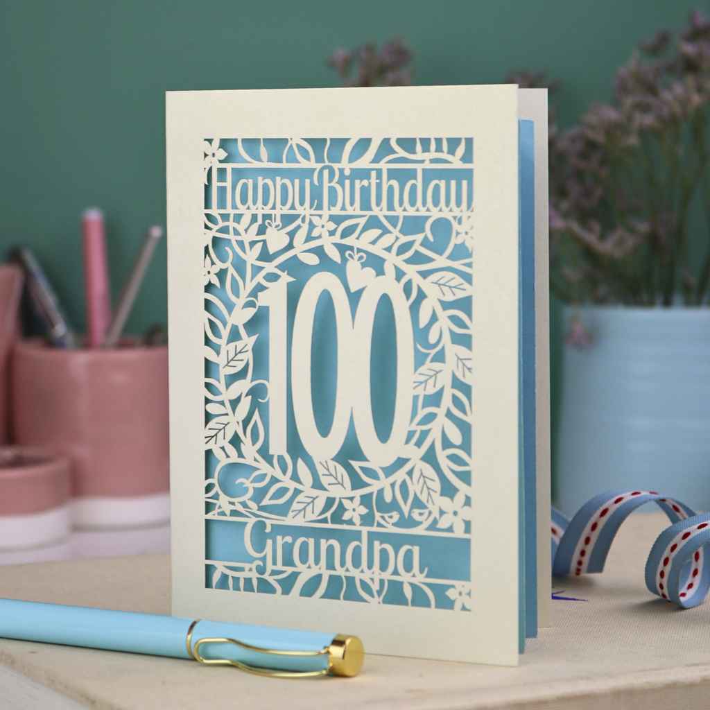 A laser cut 100th birthday card with floral '100' cut out design, 'Happy Birthday' text, and personalised with a name. 
