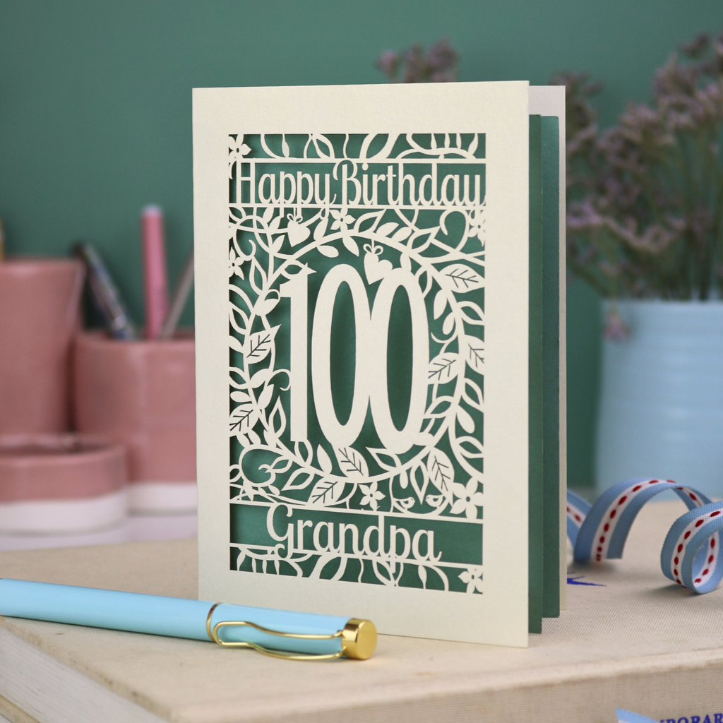 A laser cut 100th birthday card with floral '100' cut out design, 'Happy Birthday' text, and personalised with a name. 