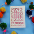 Decorative paper cut out 100th birthday card with '100 Albert' on a blue background with colourful pom-poms.