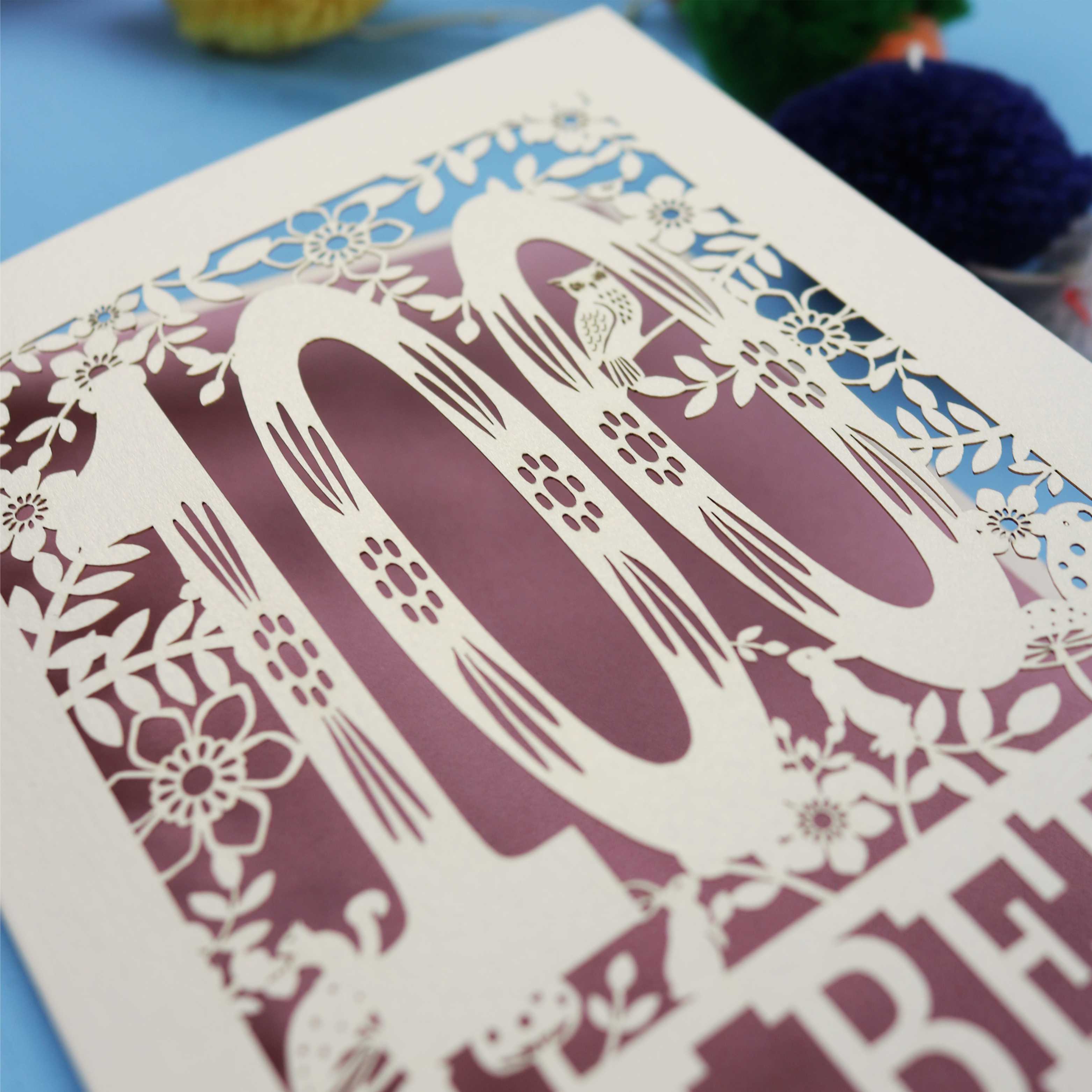 Decorative paper cut out 100th birthday card with '100 Albert' on a blue background with colourful pom-poms.