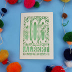 Decorative paper cut out 100th birthday card with '100 Albert' on a blue background with colourful pom-poms.
