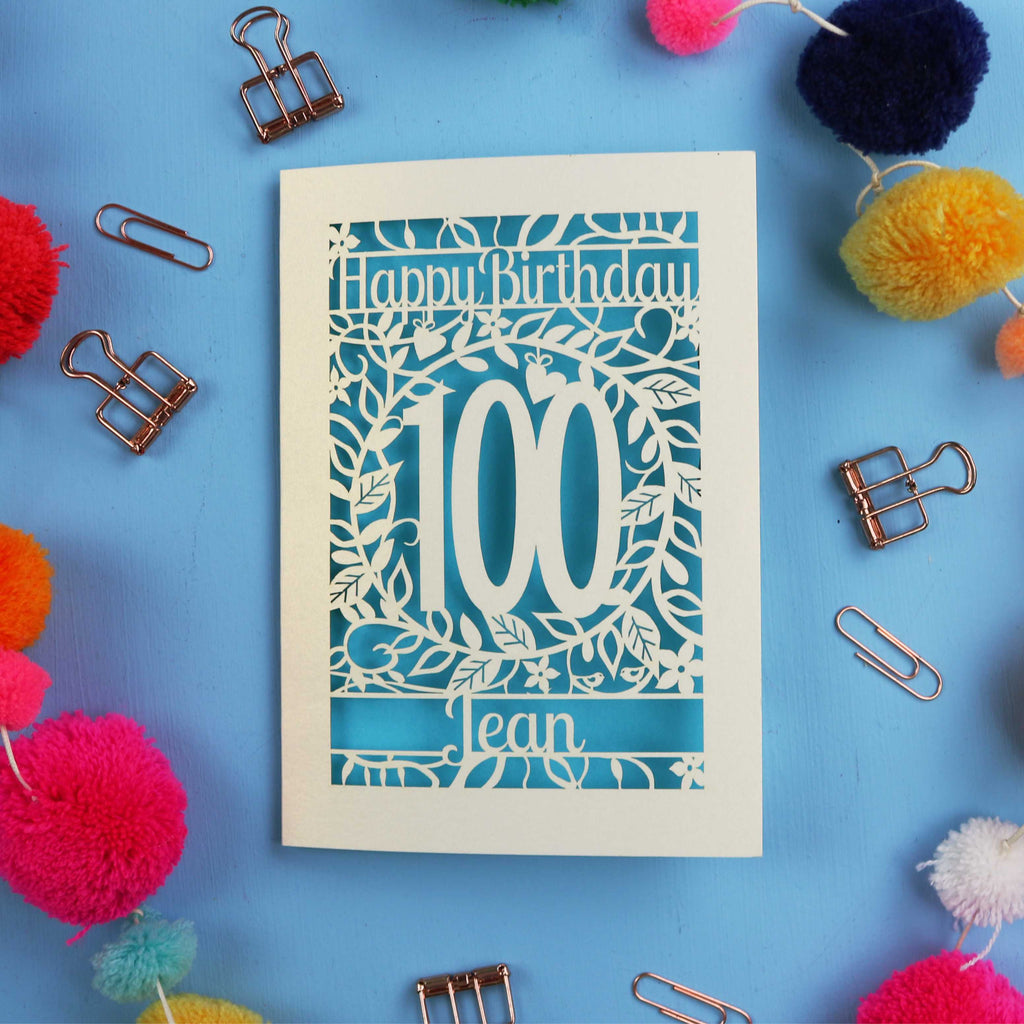 Laser cut 100th birthday card with decorative elements on a blue background