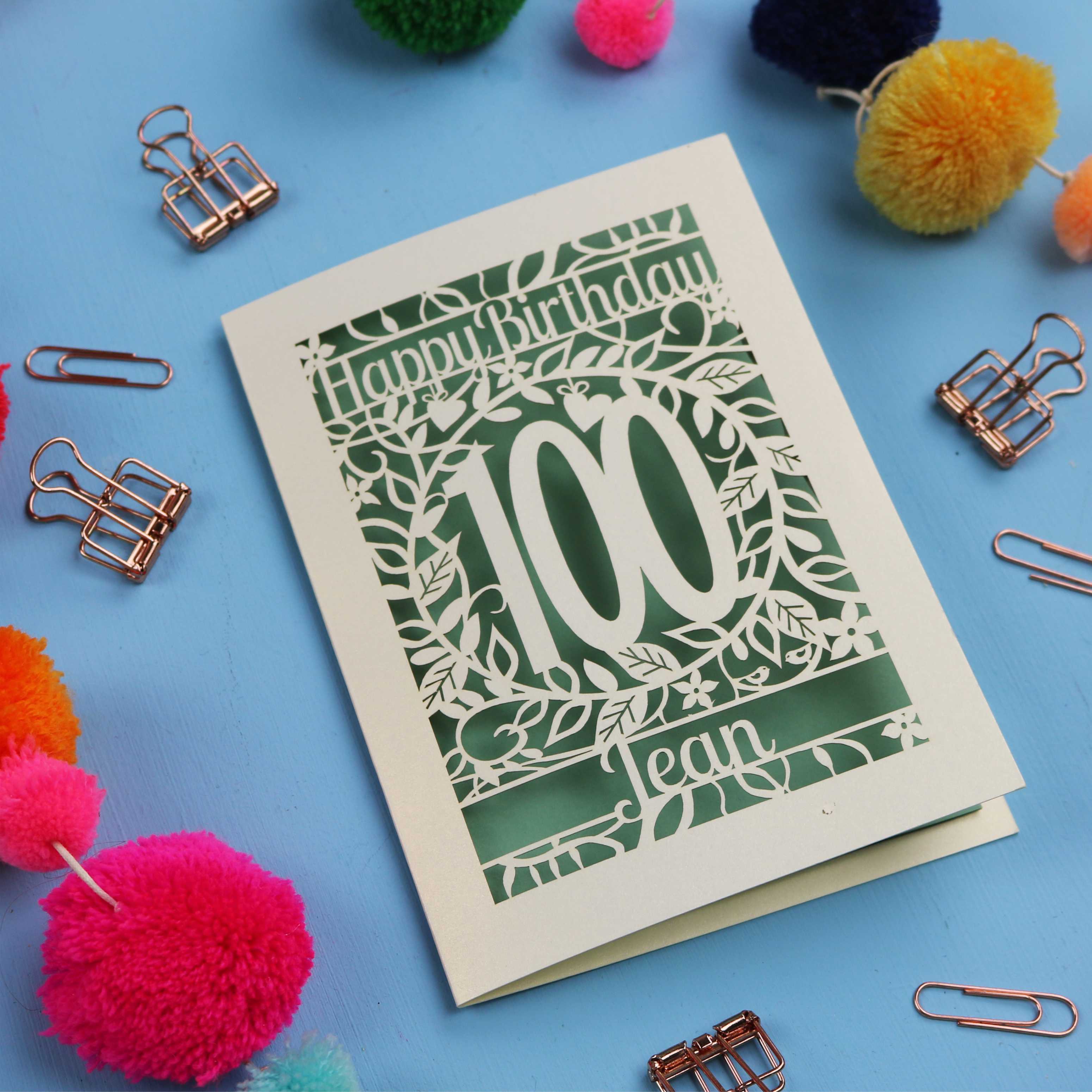 Laser cut 100th birthday card with decorative elements on a blue background