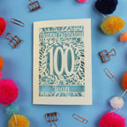 Laser cut 100th birthday card with decorative elements on a blue background