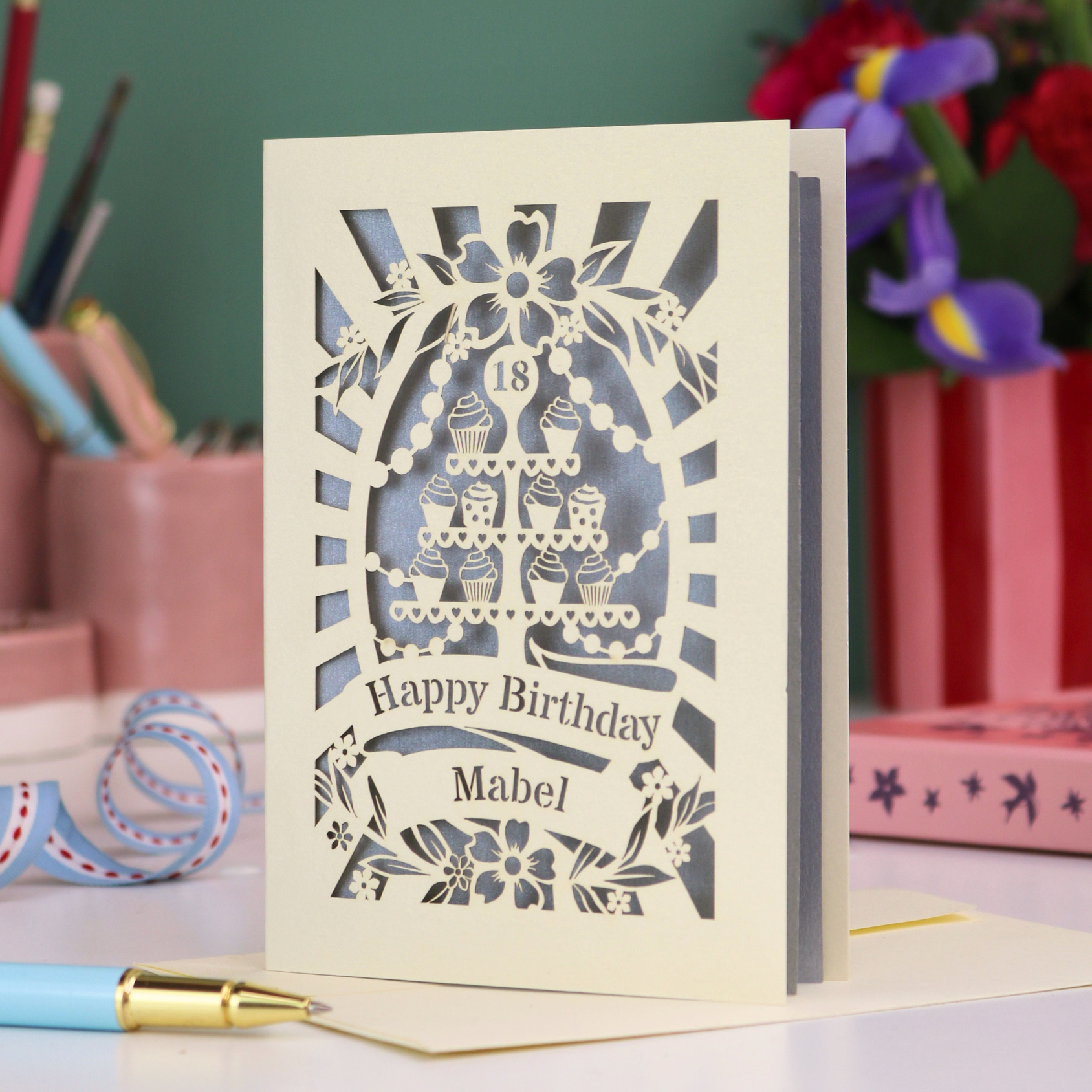 Laser-cut 18th birthday card with decorative elements on a desk with stationery items.