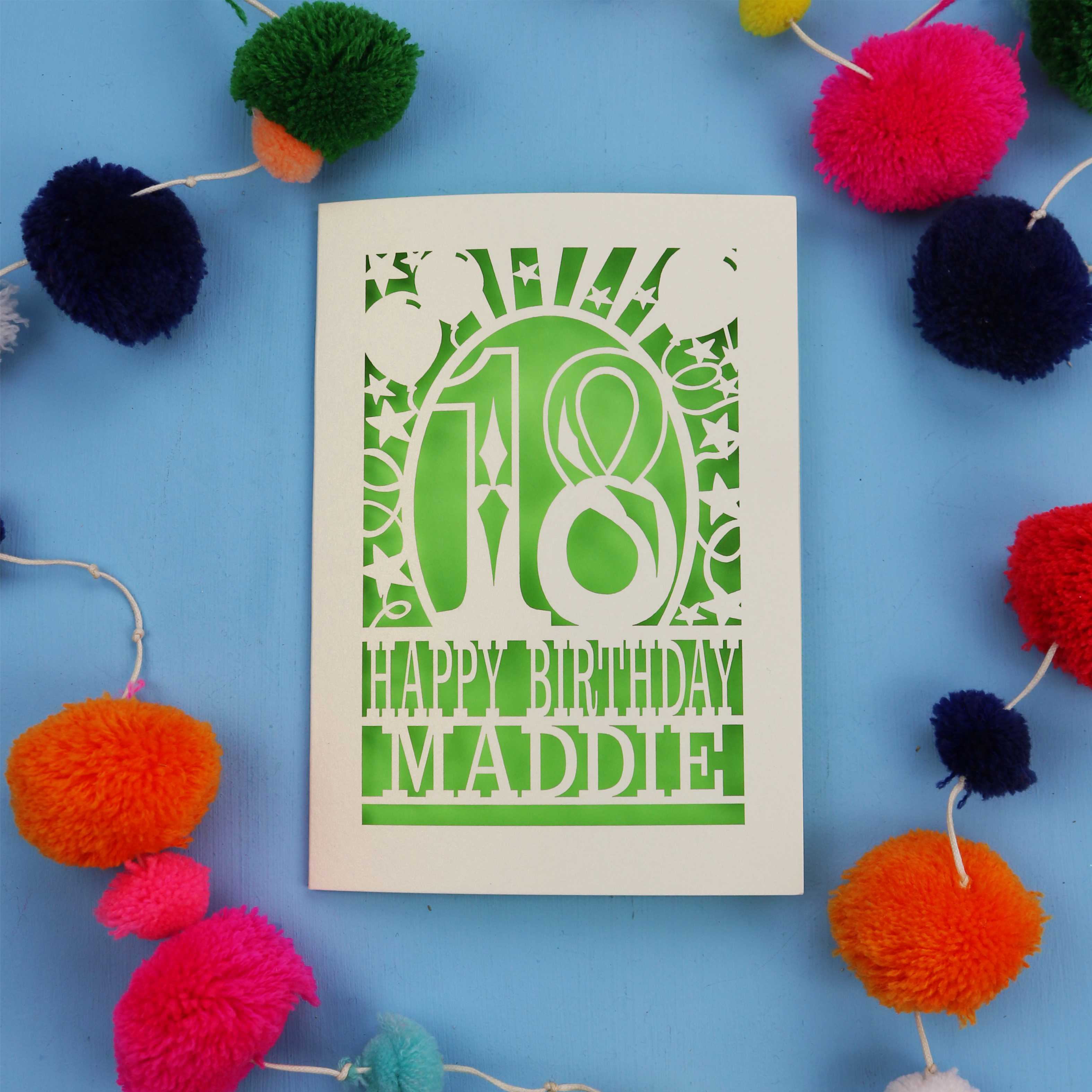 18th Birthday card with 'Happy Birthday Maddie' on a blue background with colourful pom-poms