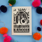 18th Birthday card with 'Happy Birthday Maddie' on a blue background with colourful pom-poms