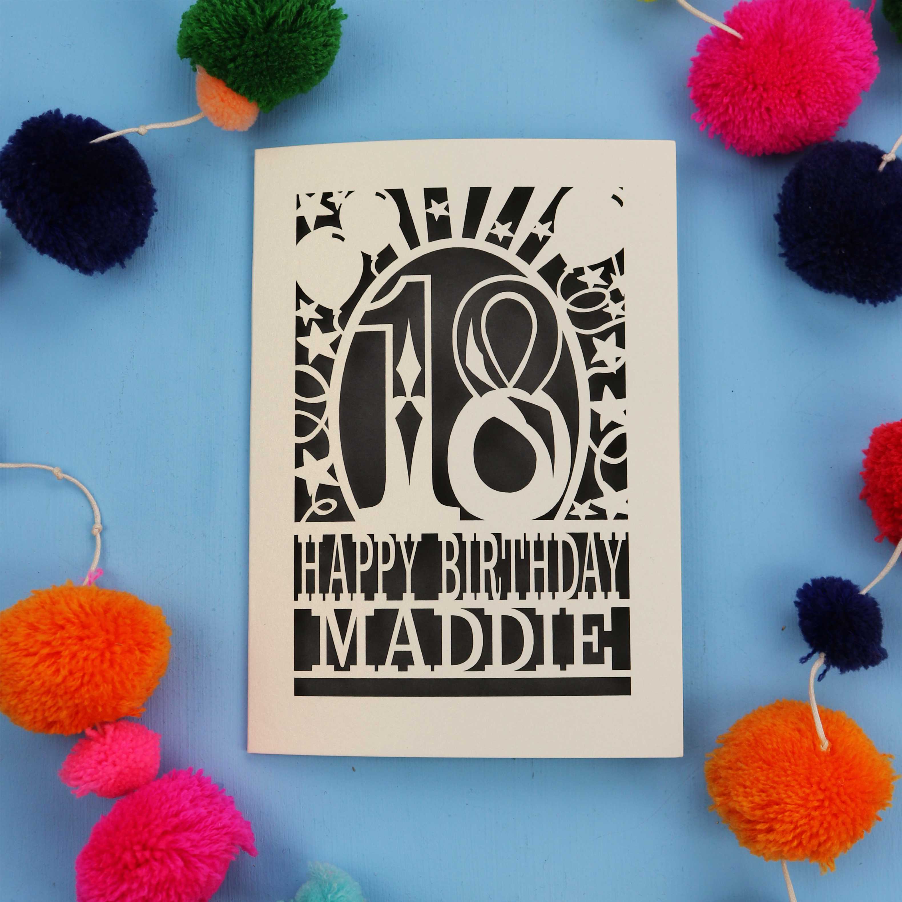 18th Birthday card with 'Happy Birthday Maddie' on a blue background with colourful pom-poms