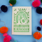 18th Birthday card with 'Happy Birthday Maddie' on a blue background with colourful pom-poms
