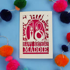 18th Birthday card with 'Happy Birthday Maddie' on a blue background with colourful pom-poms