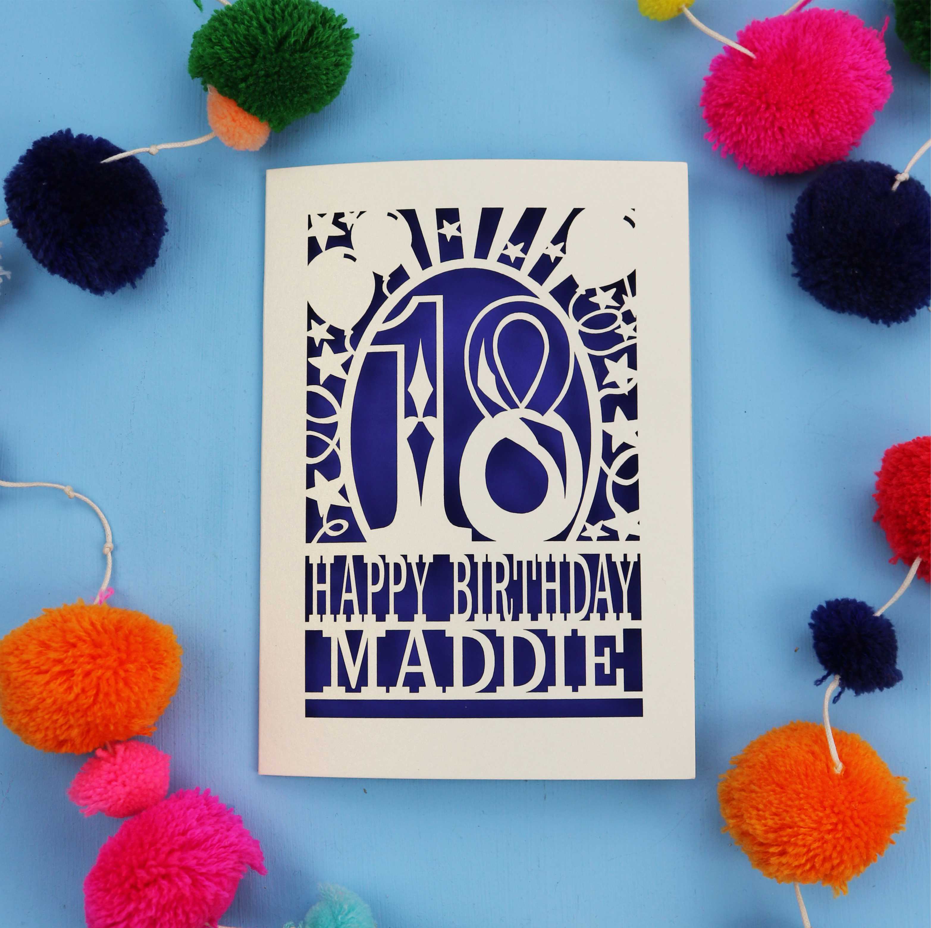 18th Birthday card with 'Happy Birthday Maddie' on a blue background with colourful pom-poms