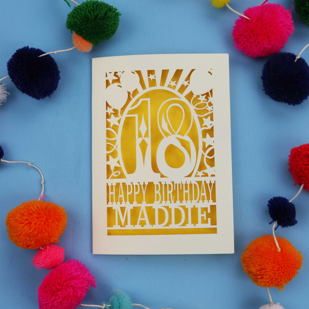 18th Birthday card with 'Happy Birthday Maddie' on a blue background with colourful pom-poms