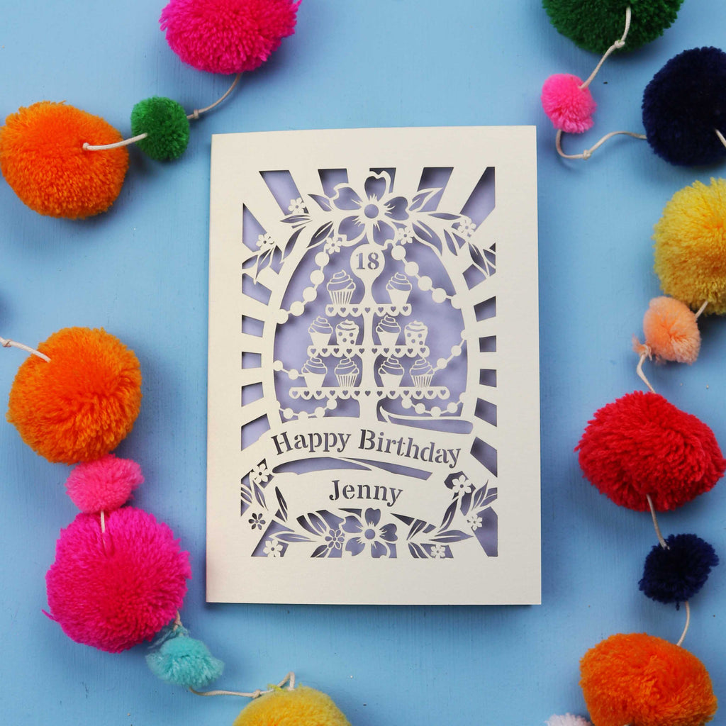 Laser-cut 18th birthday card with colourful pom-poms on a blue background