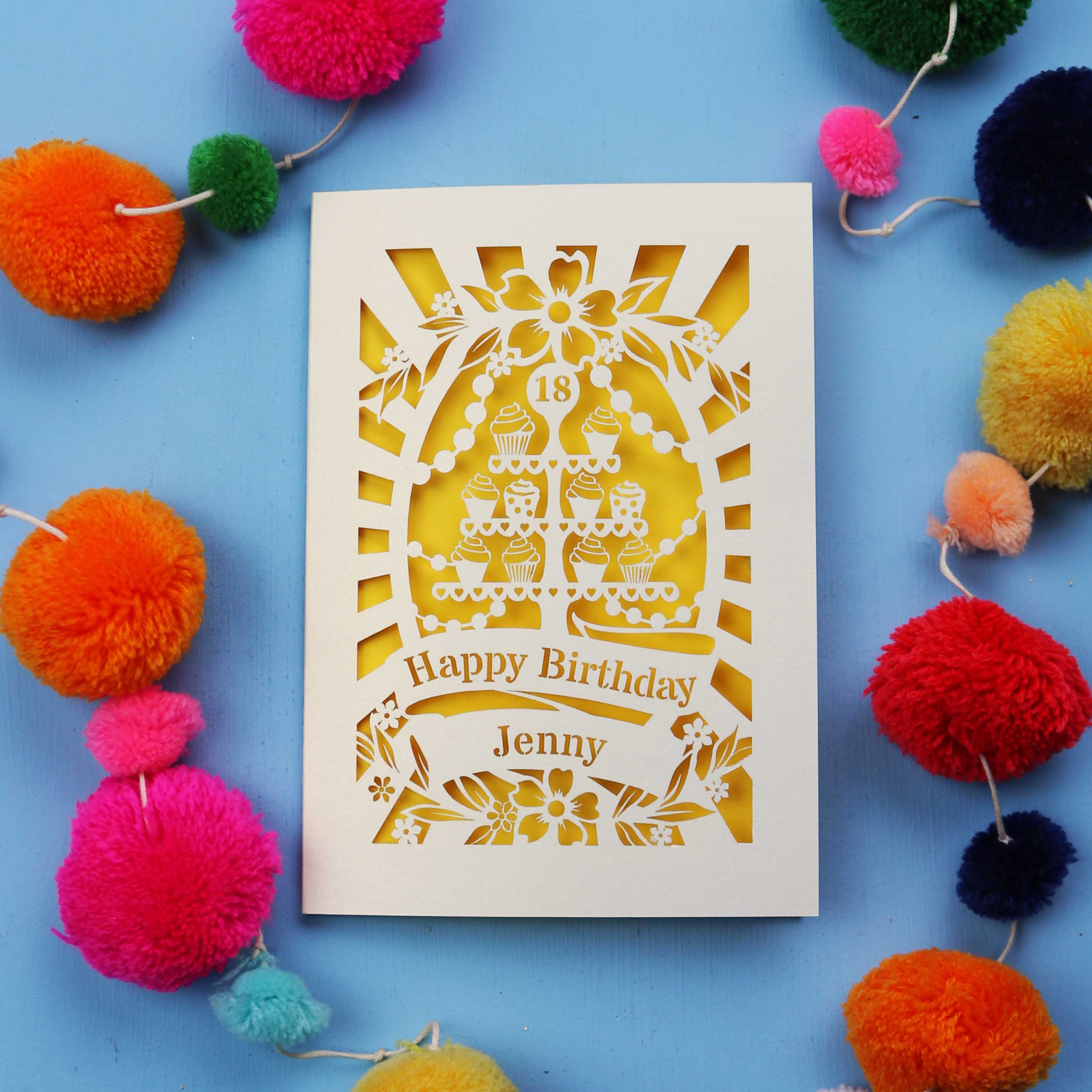 Laser-cut 18th birthday card with colourful pom-poms on a blue background