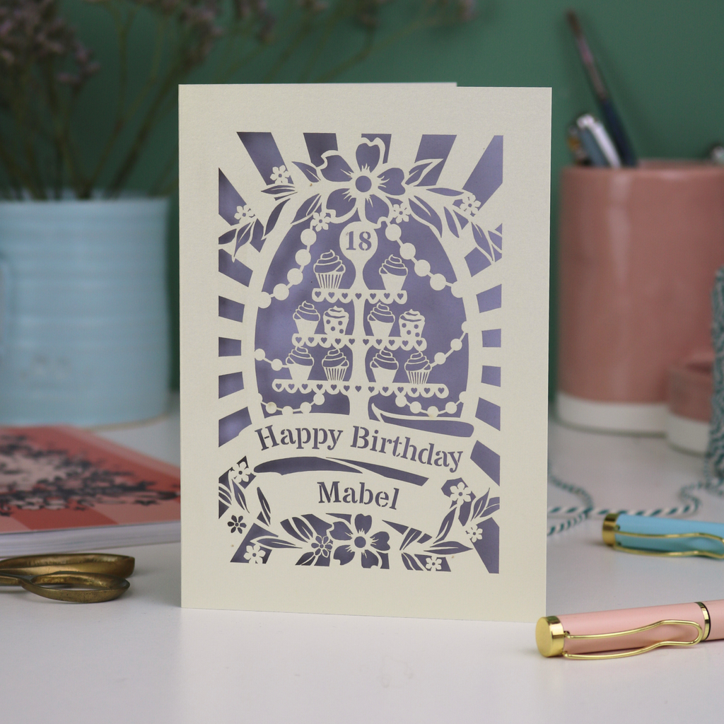 18th Birthday card with decorative cupcake stand design on a table with stationery items.