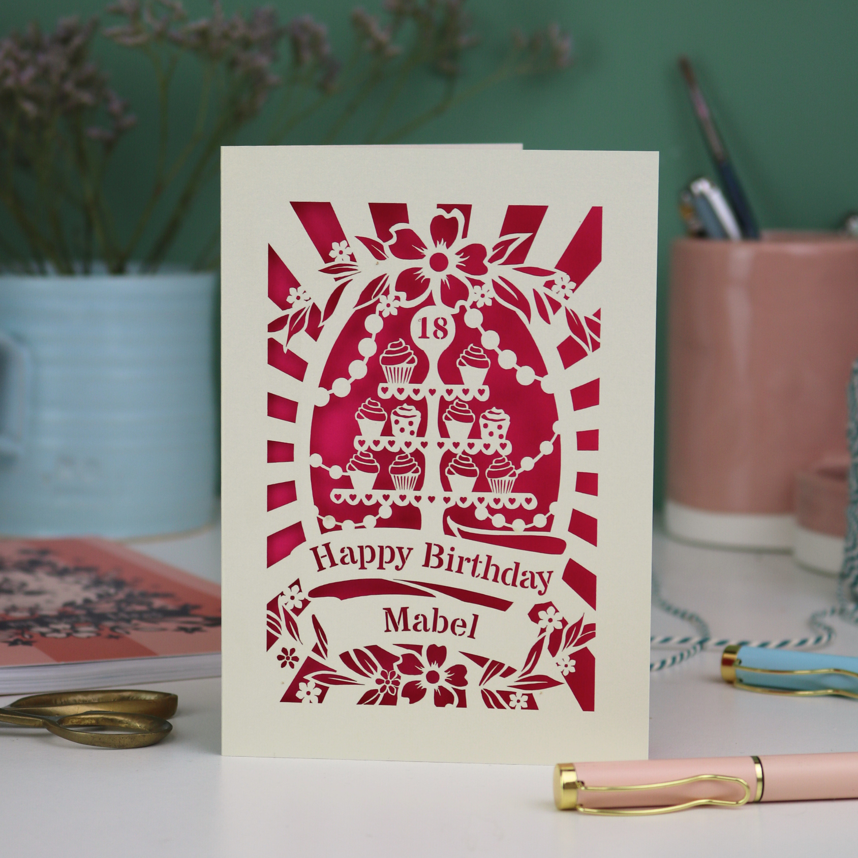 Personalised and laser cut 18th Birthday card with decorative cupcake stand design on a table with stationery items.
