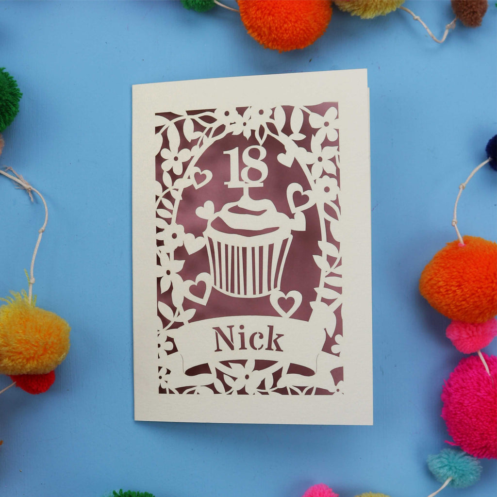 Decorative 18th birthday card with cut-out design on a blue background with colourful pom-poms.