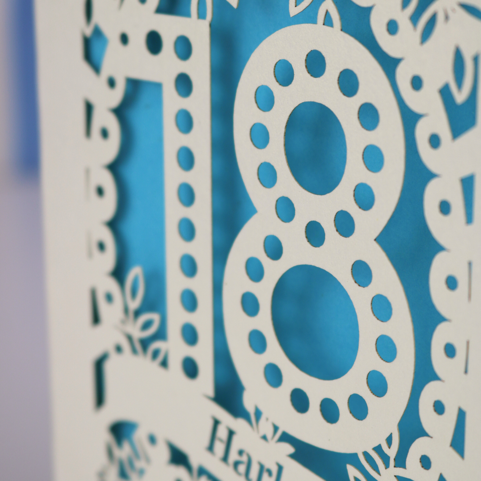 Decorative number '18' with intricate cut-out patterns on a blue background
