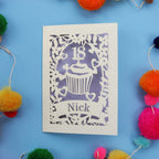 Decorative 18th birthday card with cut-out design on a blue background with colourful pom-poms.
