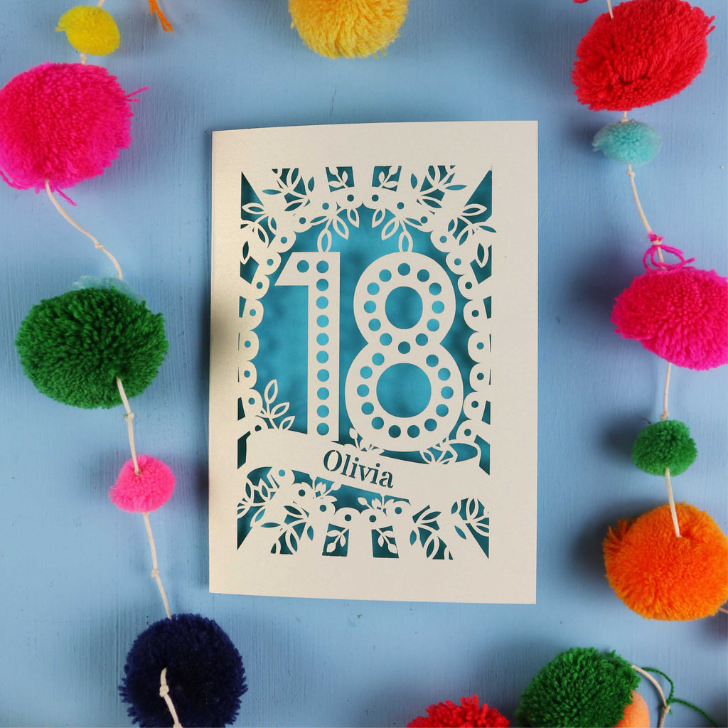 Decorative 18th birthday card with '18' and 'Olivia' on a blue background with colourful pom-poms.
