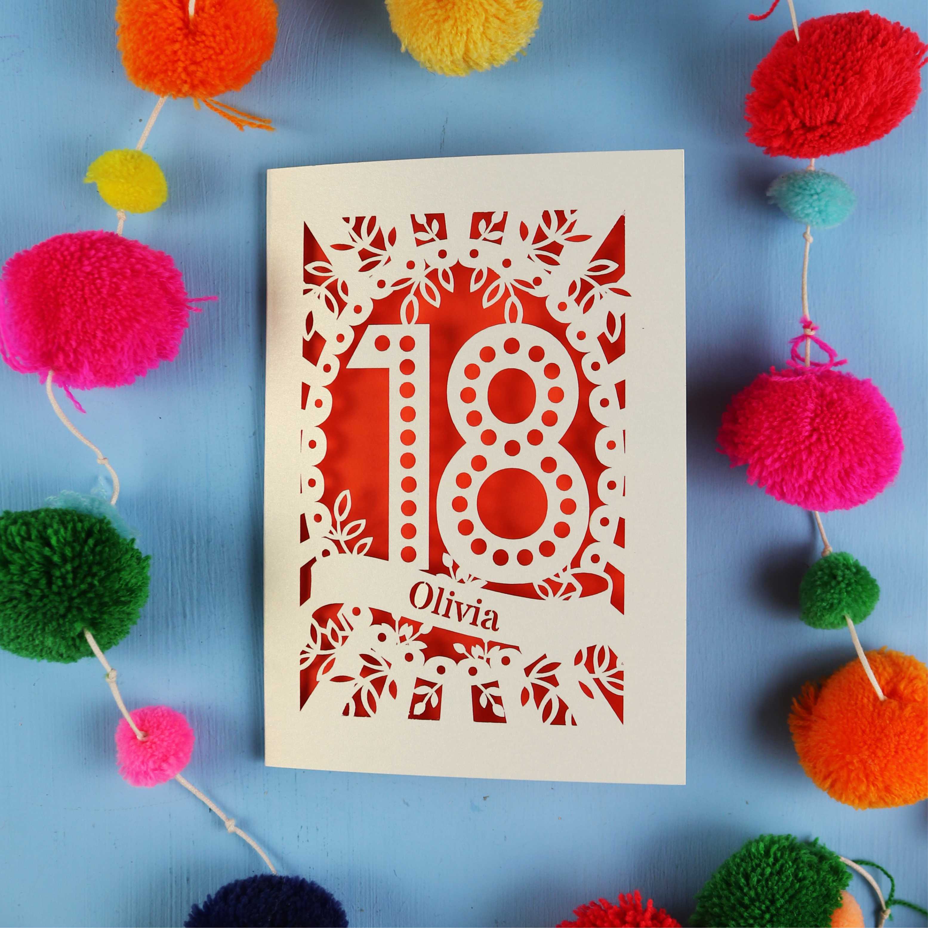 Decorative 18th birthday card with '18' and 'Olivia' on a blue background with colourful pom-poms.