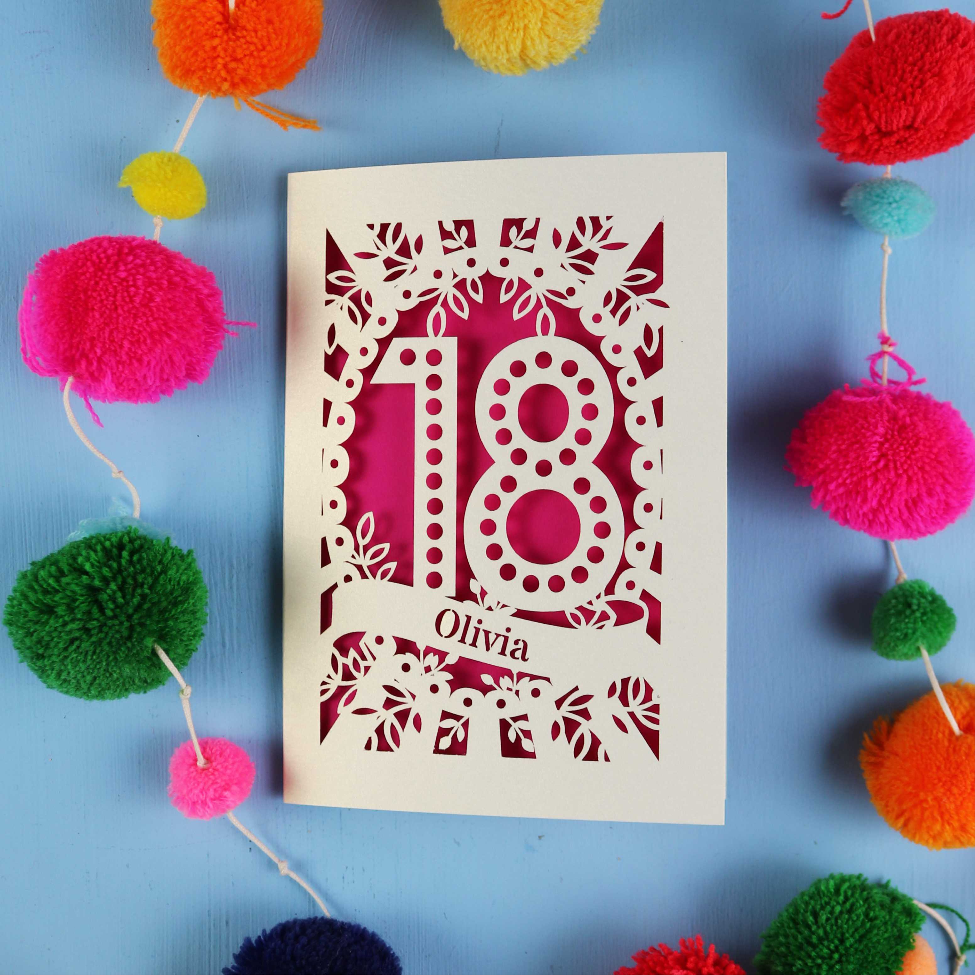 Decorative 18th birthday card with '18' and 'Olivia' on a blue background with colourful pom-poms.