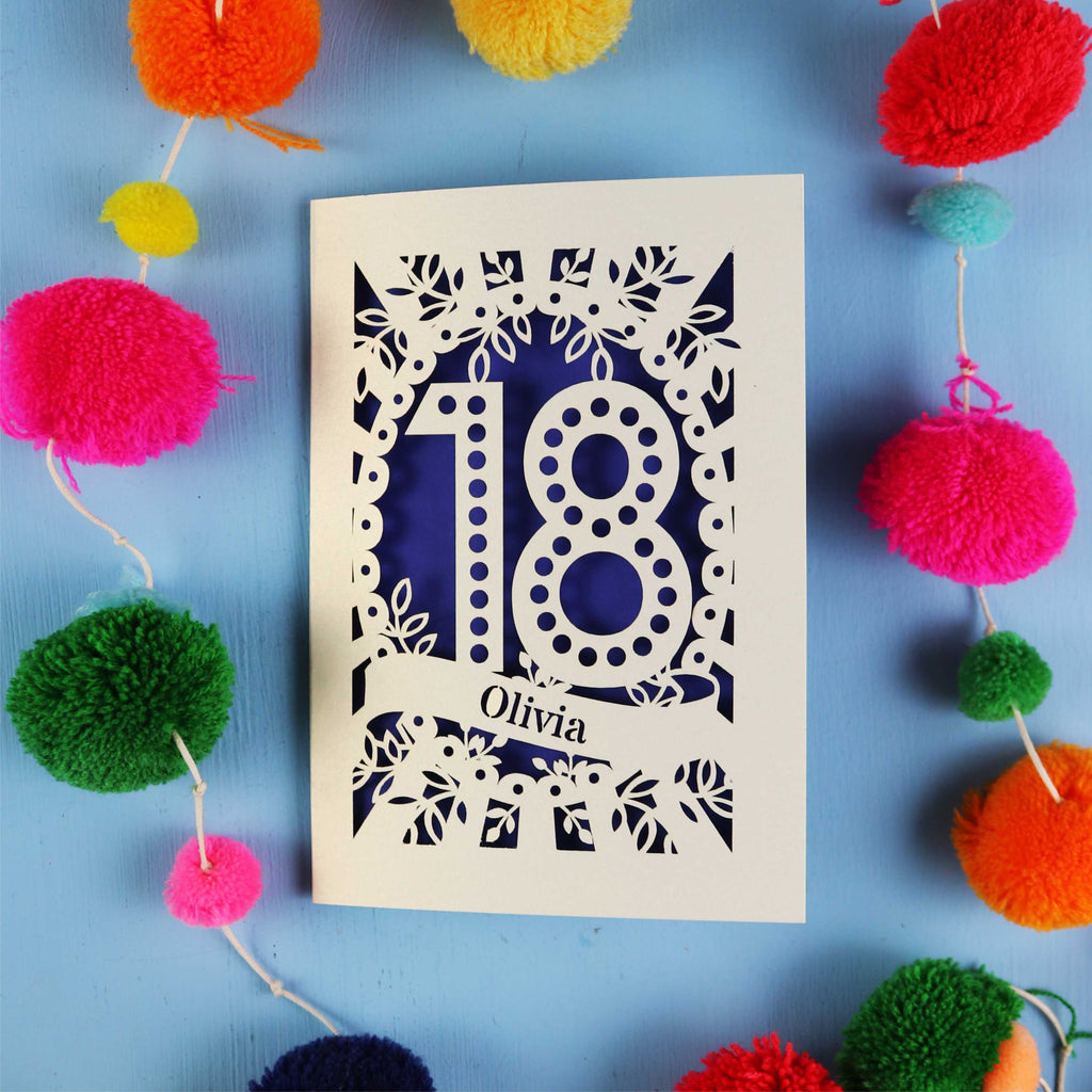 Decorative 18th birthday card with '18' and 'Olivia' on a blue background with colourful pom-poms.