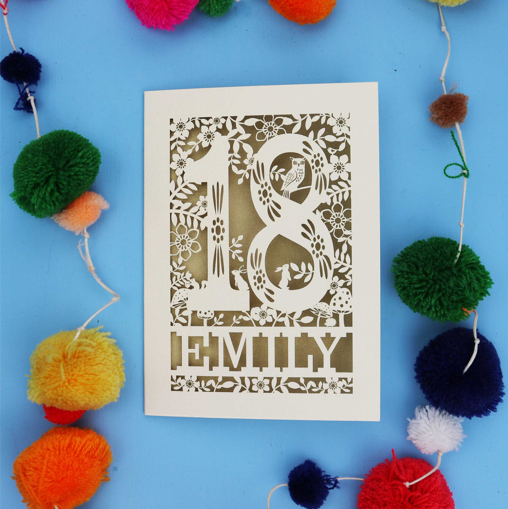 Unique 18th birthday card with floral patterns and 'EMILY' text on a blue background with colourful pom-poms.