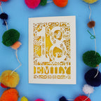 Pretty 18th birthday card with floral patterns and 'EMILY' text on a blue background with colourful pom-poms.