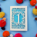 1st wedding anniversary Card with cut-out design on a blue background with colourful pom-poms