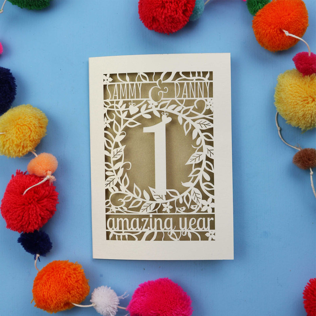 Paper wedding anniversary Card with cut-out design on a blue background with colourful pom-poms
