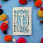 1st wedding anniversary Card with cut-out design on a blue background with colourful pom-poms